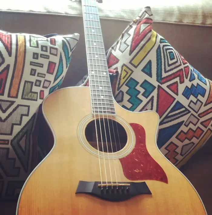An acoustic guitar on a couch with patterned cushions