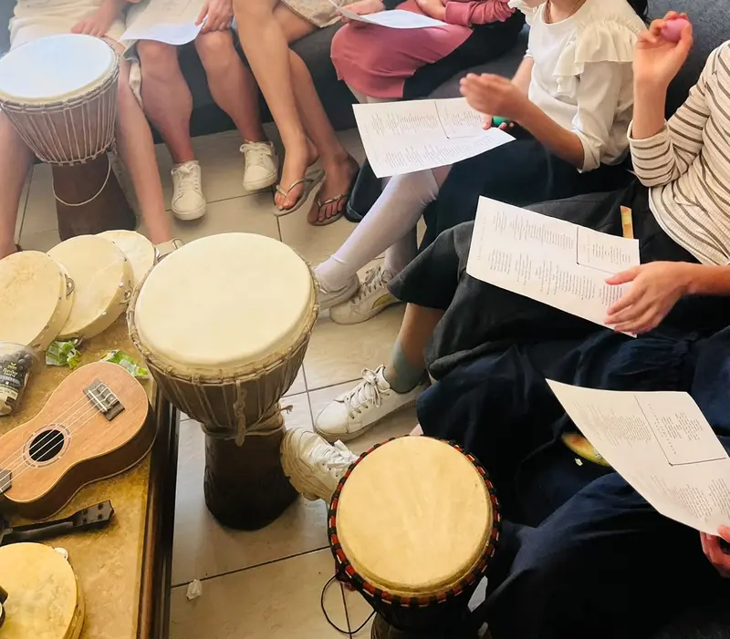 Teenagers in a music therapy workshop in Johannesburg with djembe drums, a ukulele and song lyric sheets