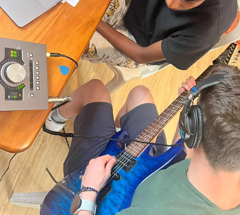 An adolescent playing electric guitar through an audio interface during a session