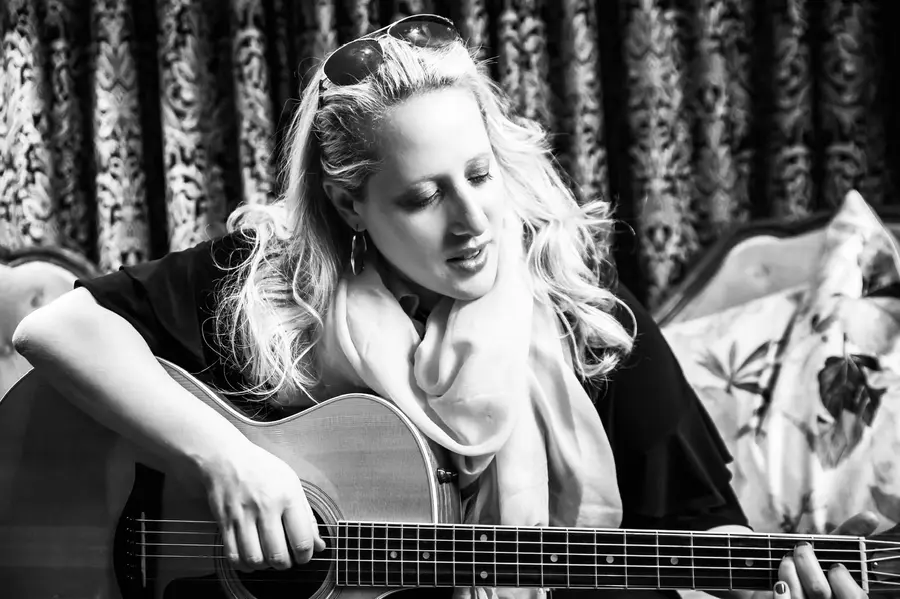 Yael Gavronsky smiling as she plays acoustic guitar